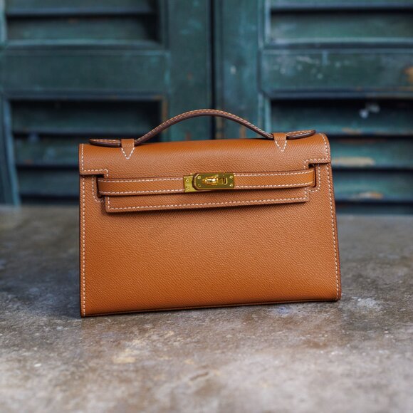 Brown leather pochette bag with white hand stitches and gold-tone hardware. - Picture 1 of 9